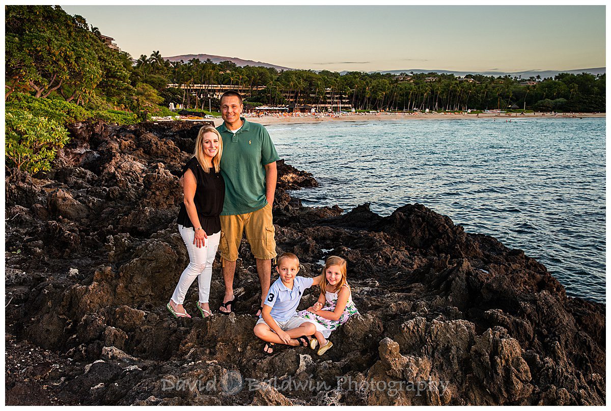 family posing at the lava rocks in front of the mauna kea beach hotel